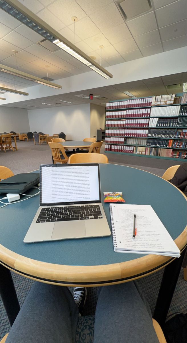 an open laptop computer sitting on top of a table in front of a book shelf