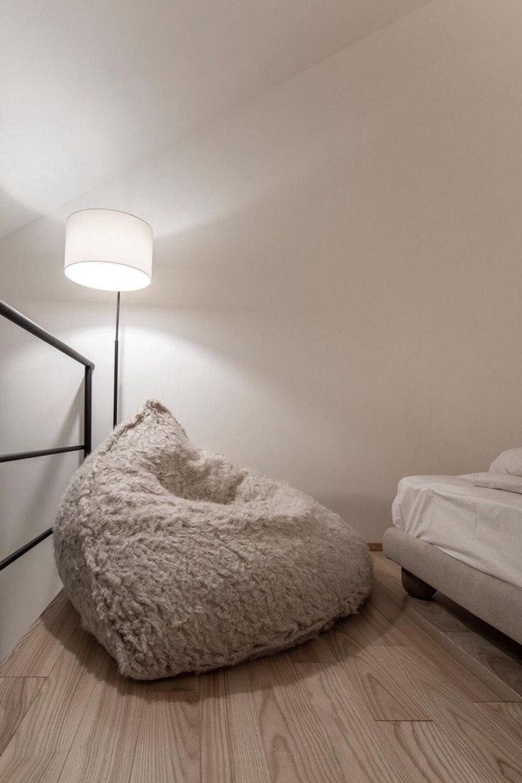 a large bean bag chair sitting on top of a hard wood floor next to a bed