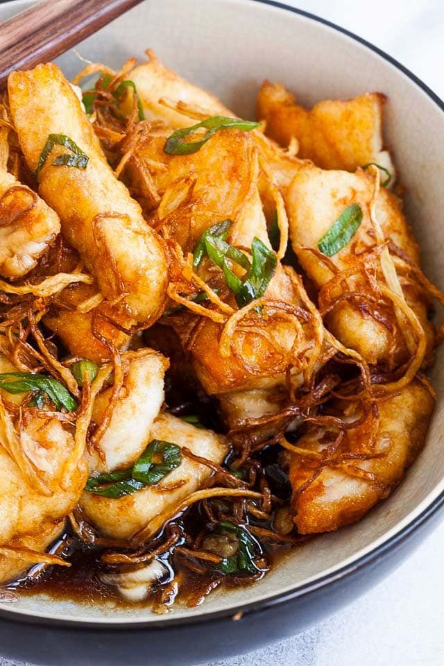 a bowl filled with fried food and chopsticks