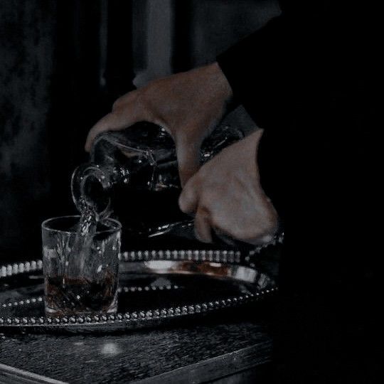 a person pouring water into a glass on top of a tray with silver trimmings