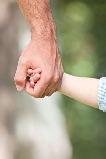 a close up of a person holding the hand of a child