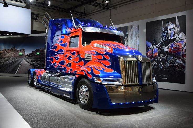 a blue and red semi truck with flames painted on it's side in a showroom