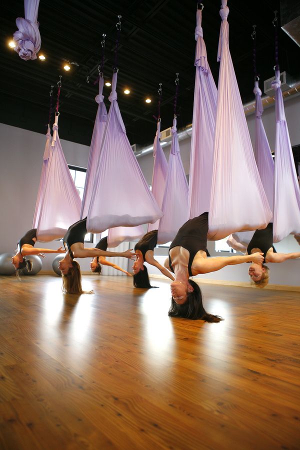 a group of women doing aerial acrobatics in front of hanging hammocks