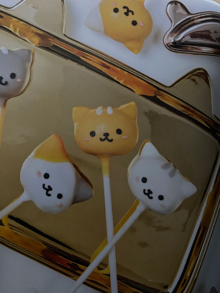 there are four cat lollipops on the plate