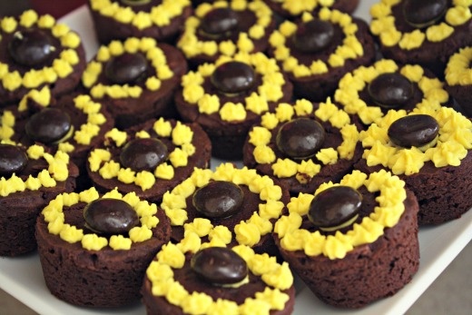 chocolate cupcakes with yellow frosting and sunflower decorations on top are arranged in a circle