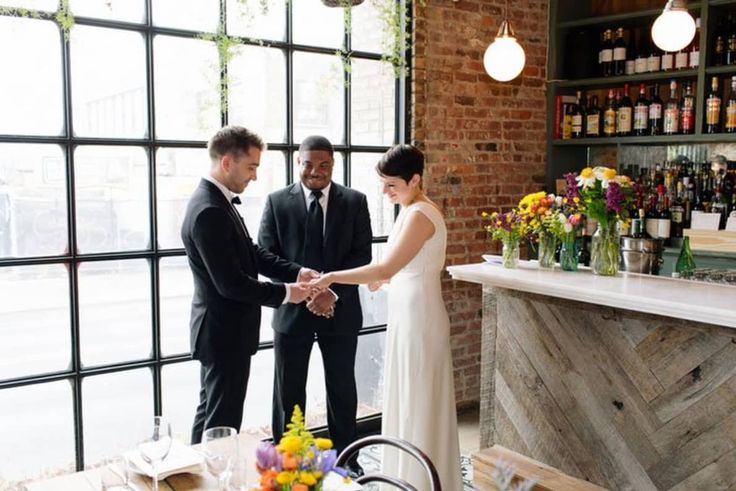 a bride and groom holding hands in front of a bar