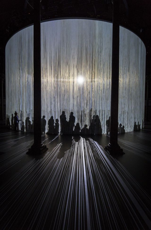 several people are sitting in front of a curtained wall with light streaming through it