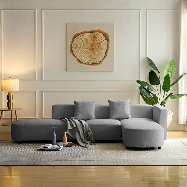 a living room with a gray couch and wooden table in the corner next to a painting on the wall