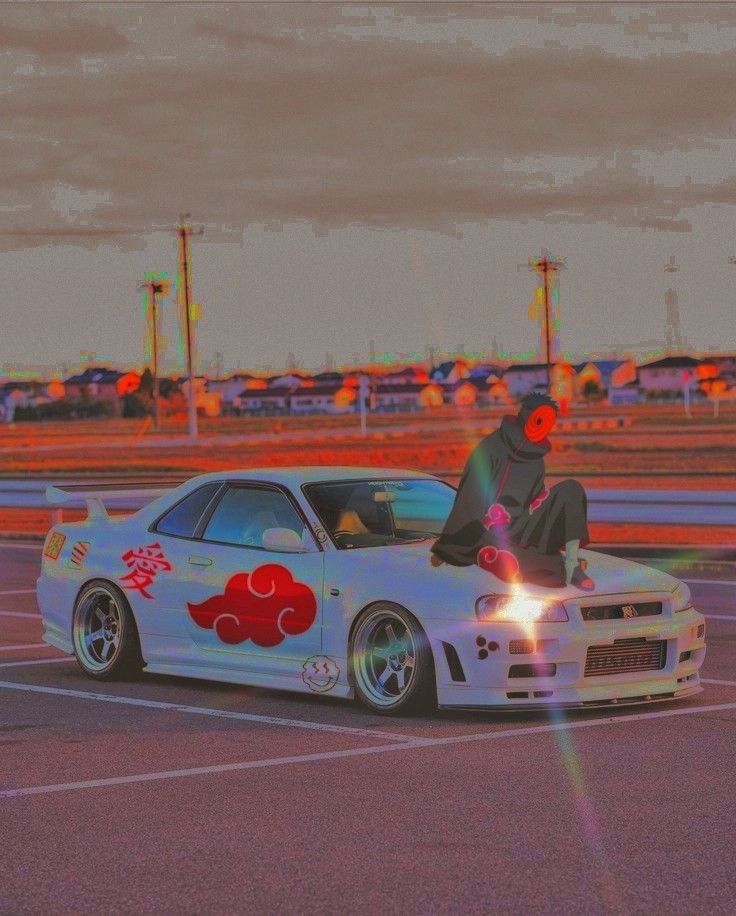 a person sitting on top of a white car in a parking lot with other cars