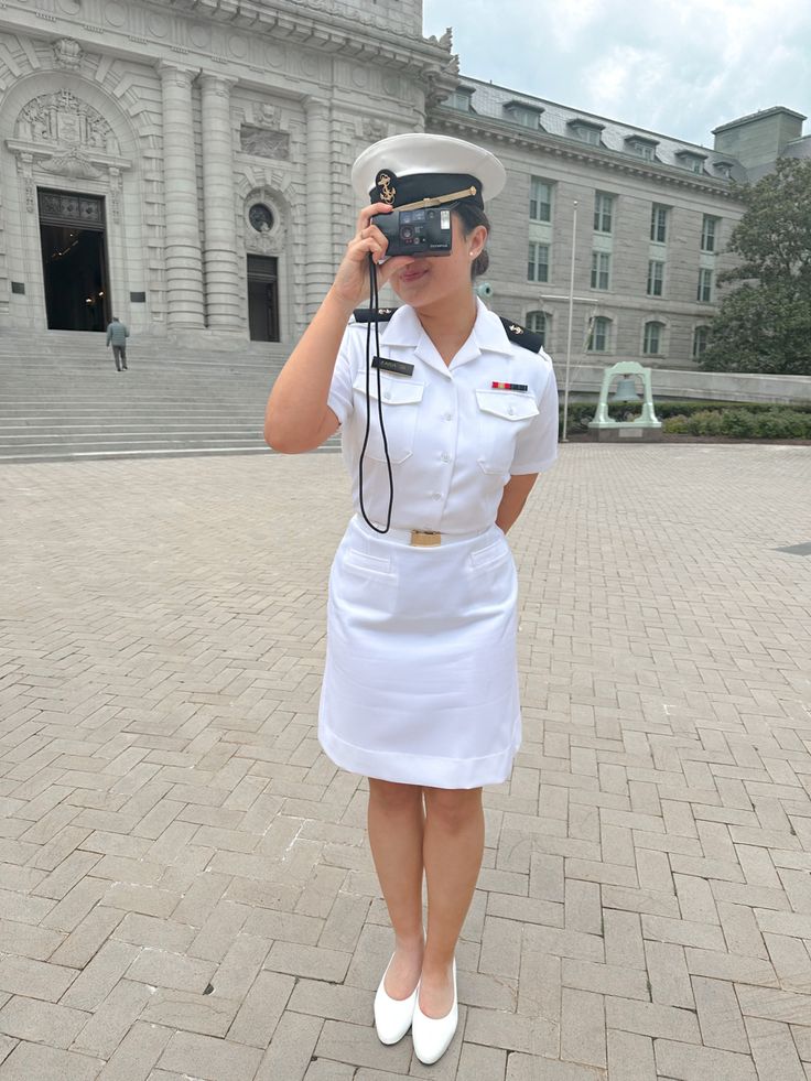 a woman in uniform is holding a camera