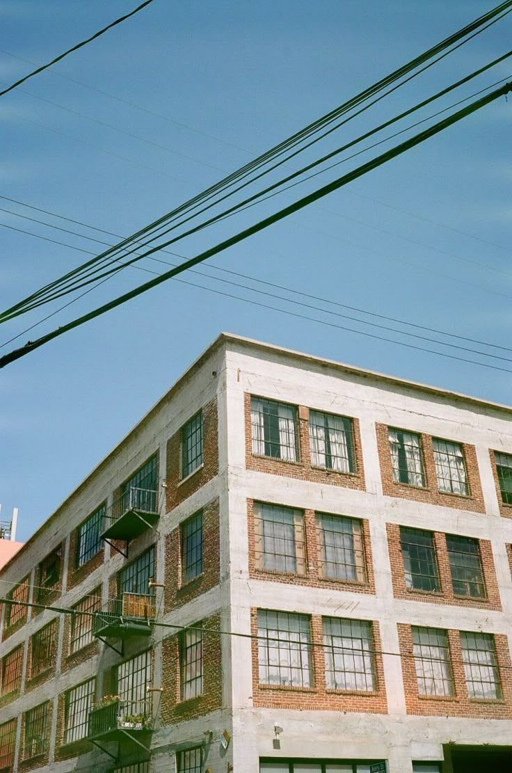 an old brick building with many windows and balconies on the top floor is surrounded by power lines