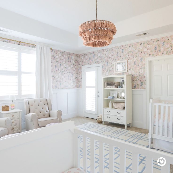 a baby's room with floral wallpaper and white furniture