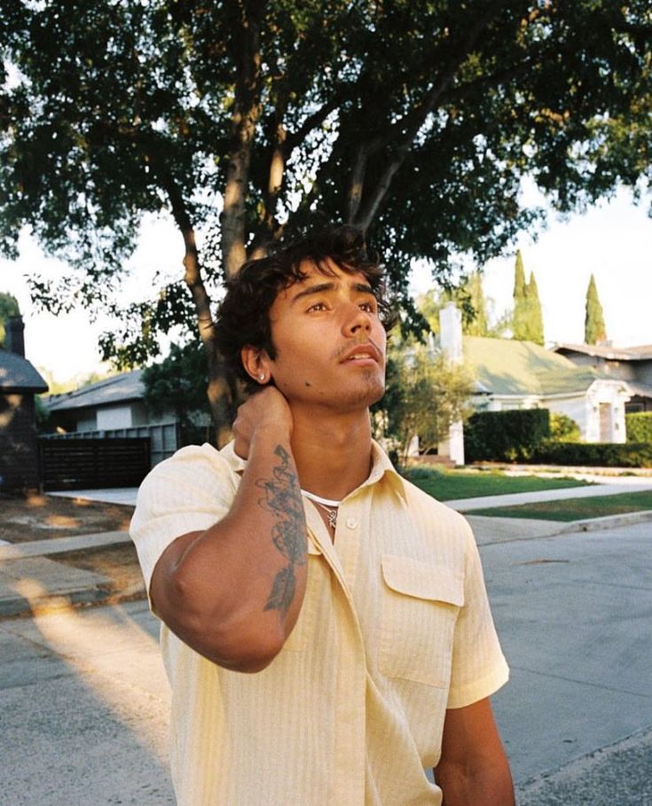 a man standing in the street talking on his cell phone and holding his hand up to his ear