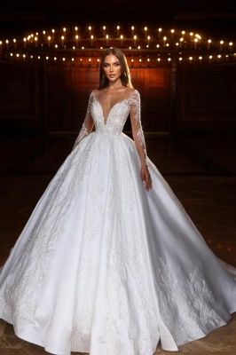 a woman in a white wedding dress posing for the camera with lights on behind her