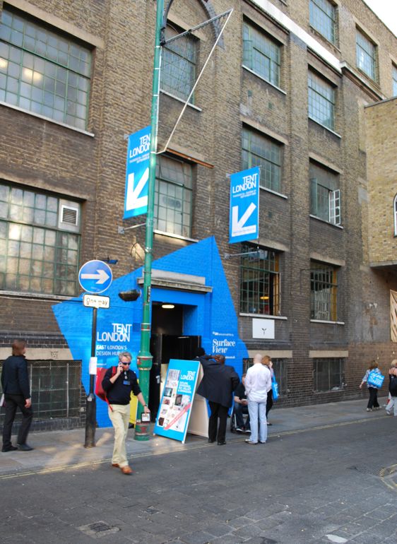 people are walking on the street in front of an old brick building with blue signs