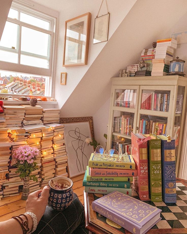 a person holding a coffee cup in front of a stack of books on a table