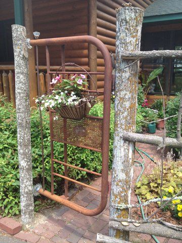 an old iron gate with flowers growing in the basket on it's front porch