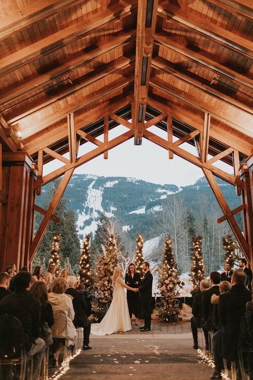 a bride and groom standing at the end of their wedding ceremony in front of a snowy mountain