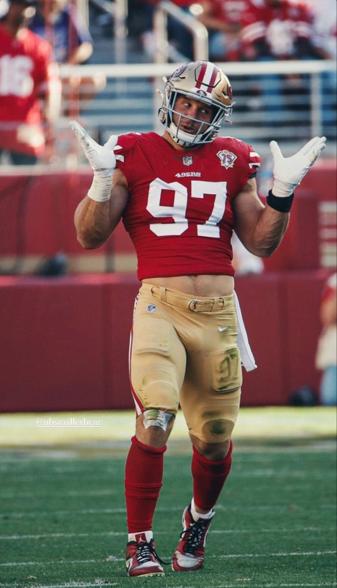 a football player is on the field with his hands in the air and one hand out