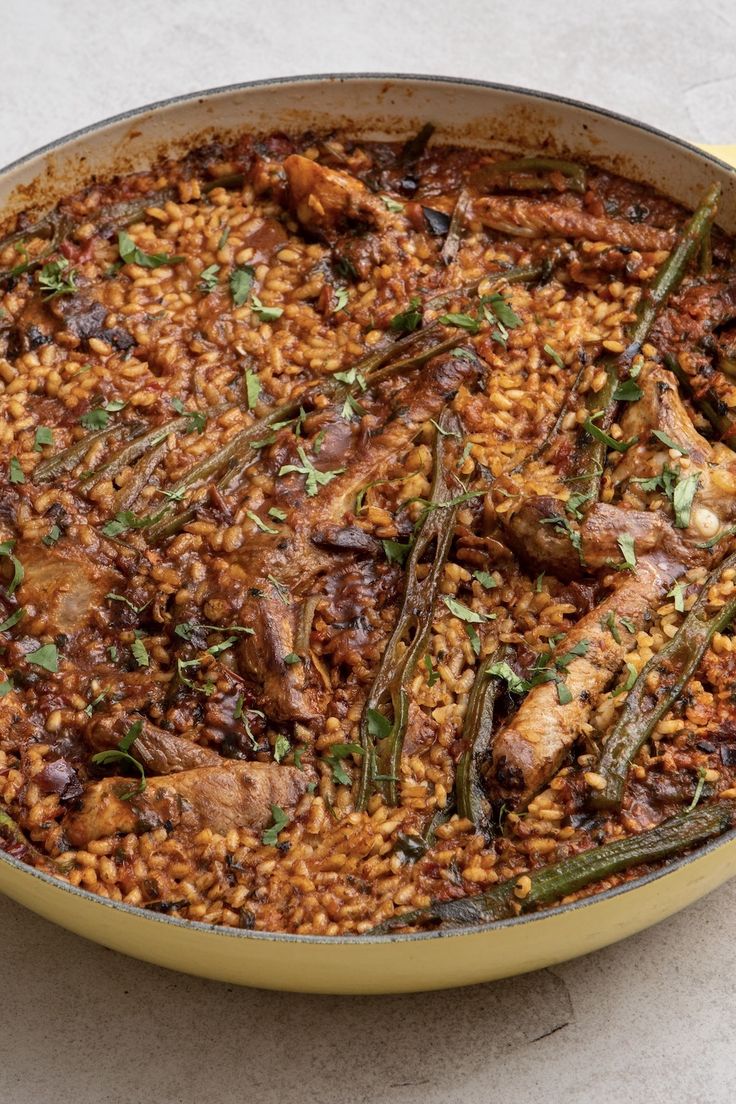 a pan filled with rice and meat covered in seasoning on top of a table