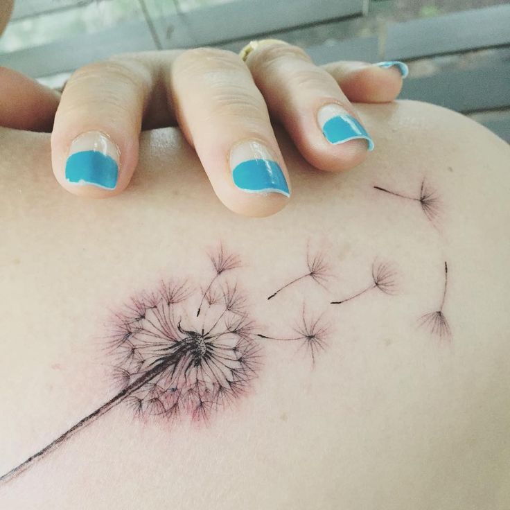 a woman's back with a dandelion tattoo on it