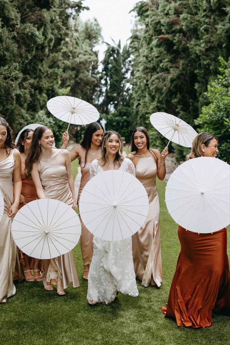 a group of women standing next to each other holding white umbrellas in their hands