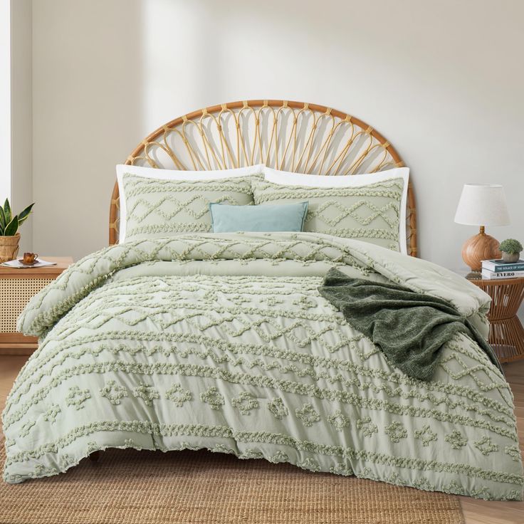 a bed with green comforter and pillows in a room next to a wicker headboard