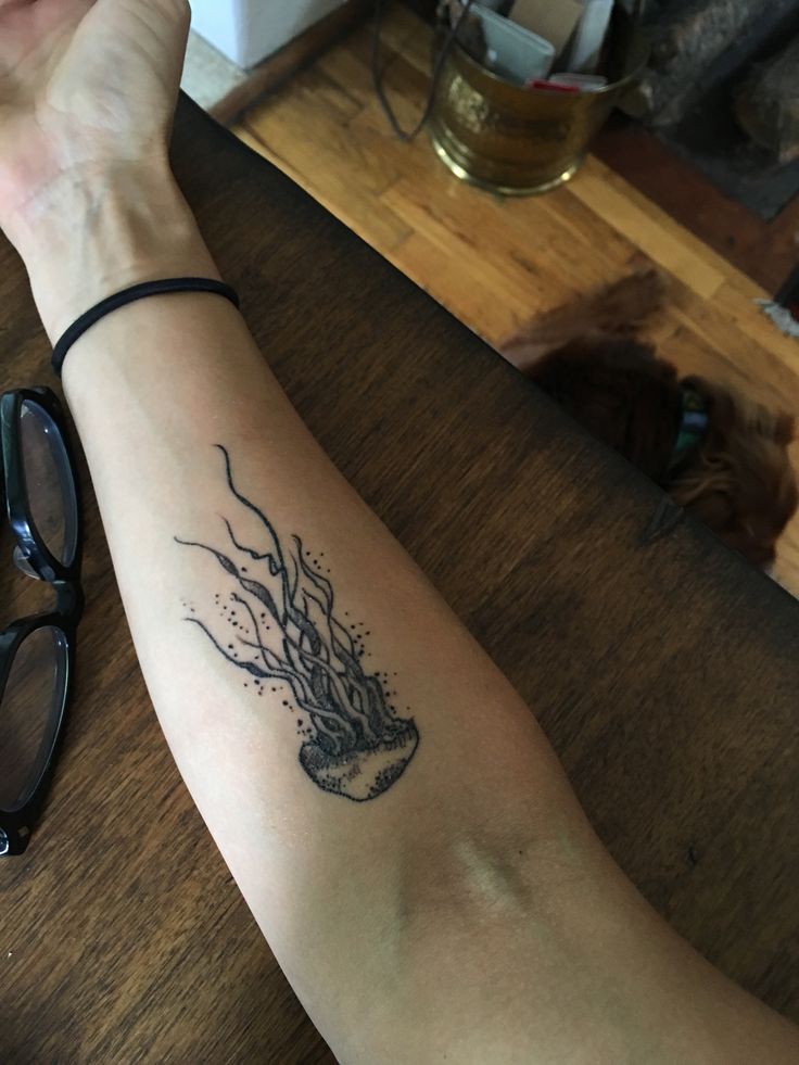 a person's arm with a tattoo on it and some glasses next to them