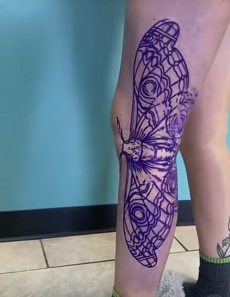 a woman's legs with tattoos on them, and her leg is covered in purple ink