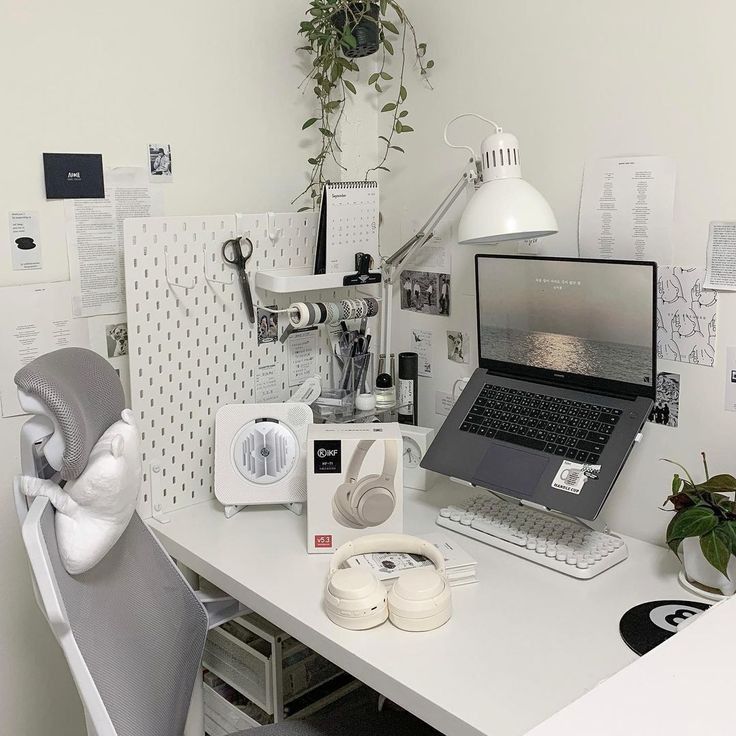 a laptop computer sitting on top of a white desk next to a phone and headphones