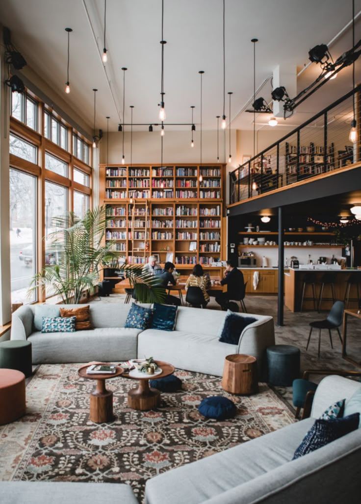 a living room filled with lots of furniture next to a tall book shelf full of books