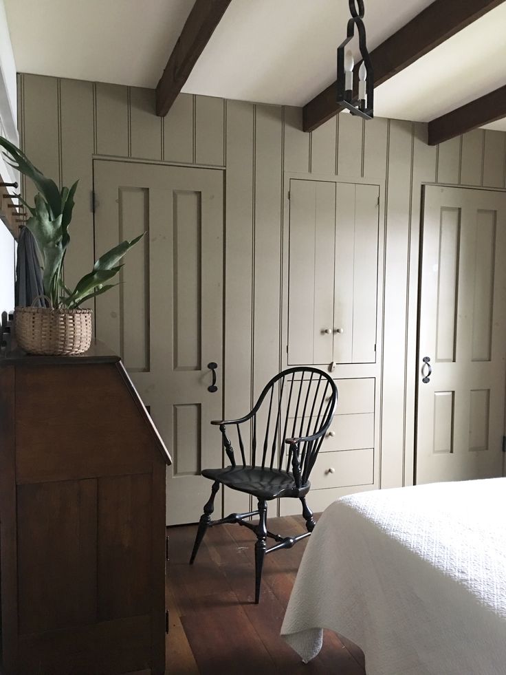 a bedroom with white bedding and wooden beams on the ceiling, along with a black rocking chair