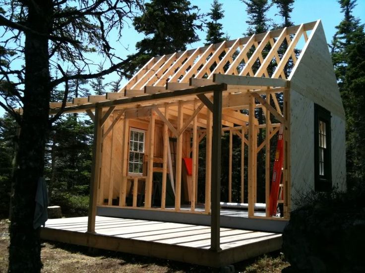 a small house is being built in the woods with wood framing on it's roof