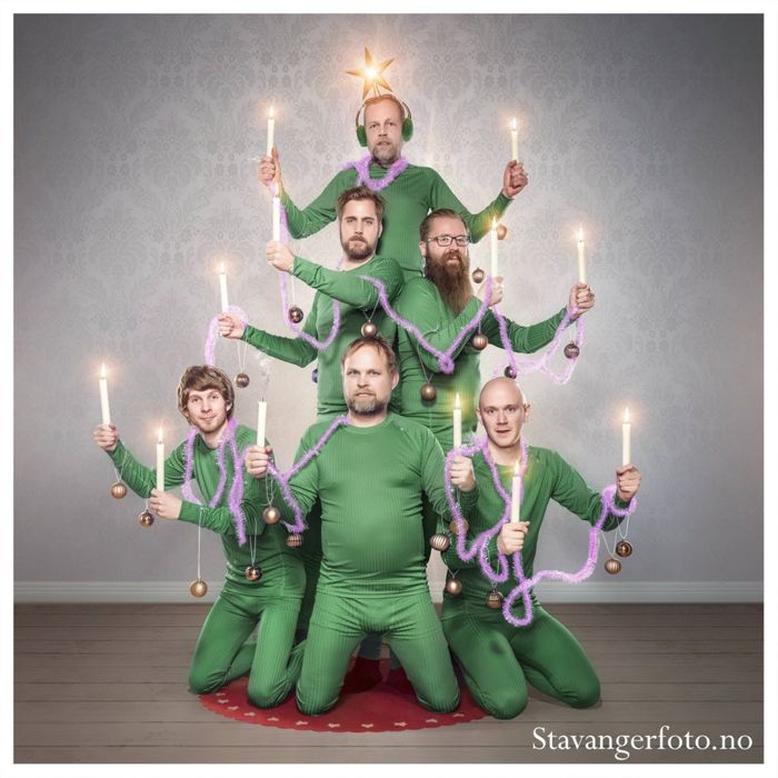 a group of men in green outfits holding candles