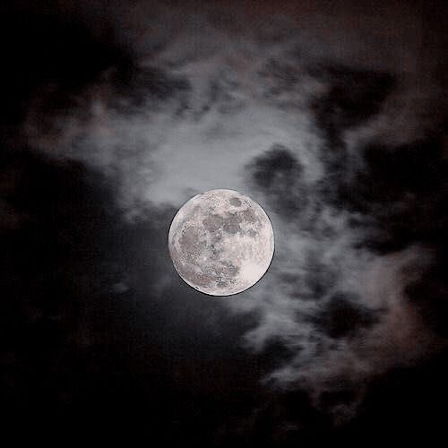 the full moon is seen through some clouds