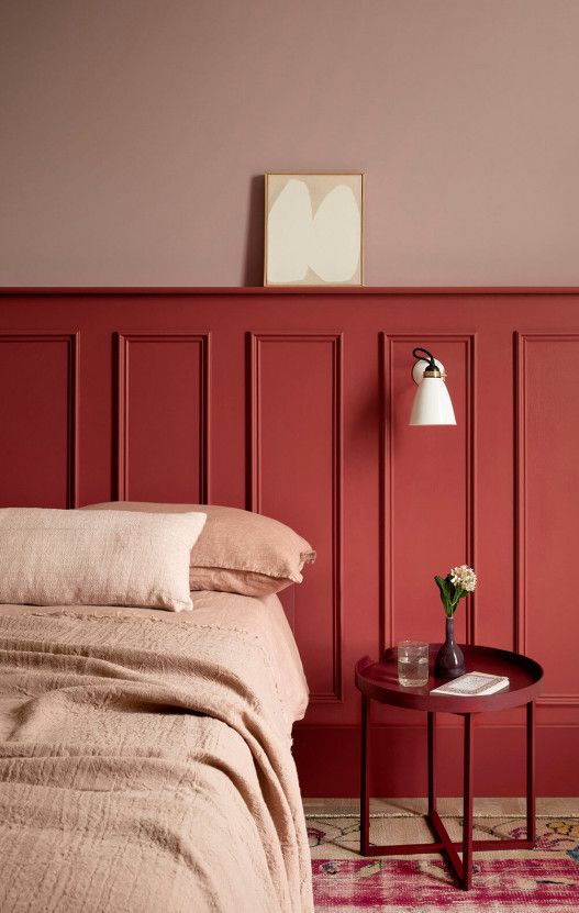 a bedroom with red walls and a bed in the corner next to a small table