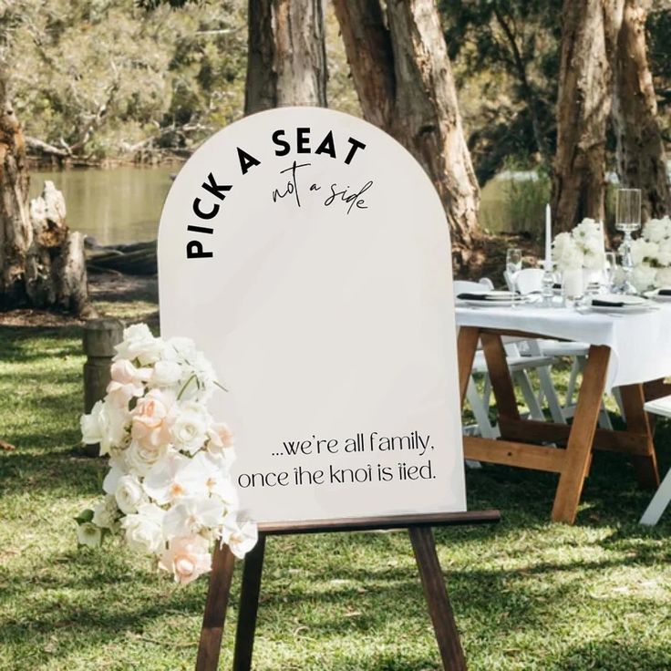 a sign that says pick a seat at the end of a table with flowers on it