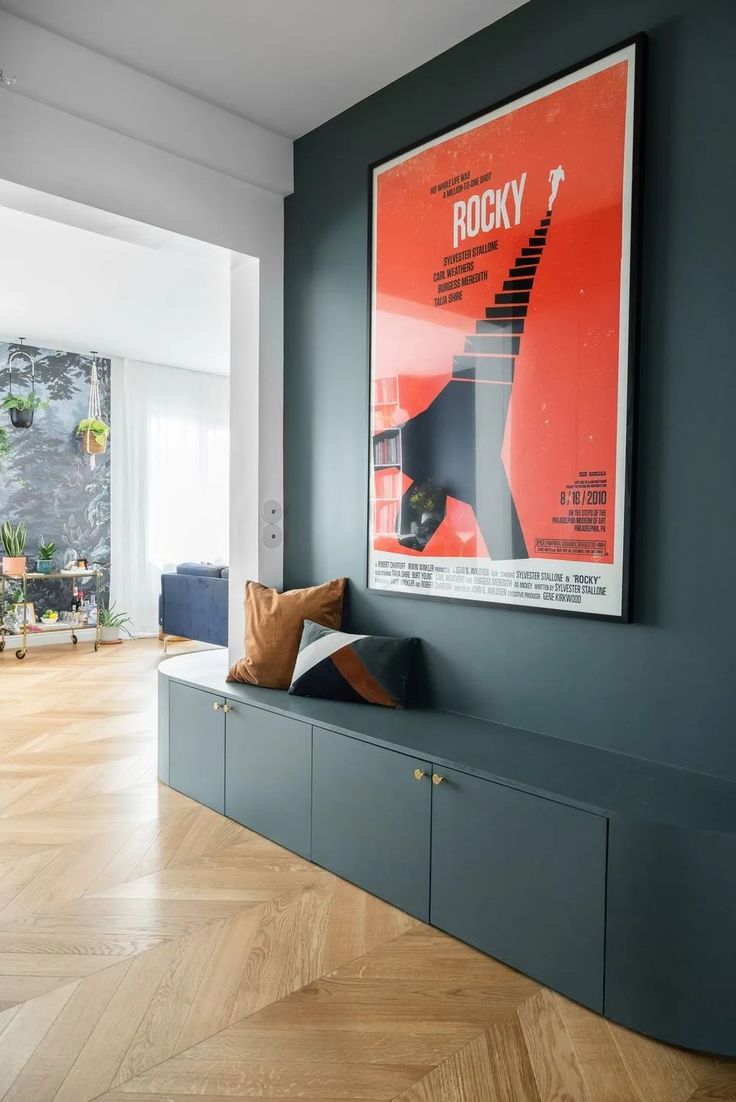 a poster hangs on the wall above a bench in a room with wood flooring