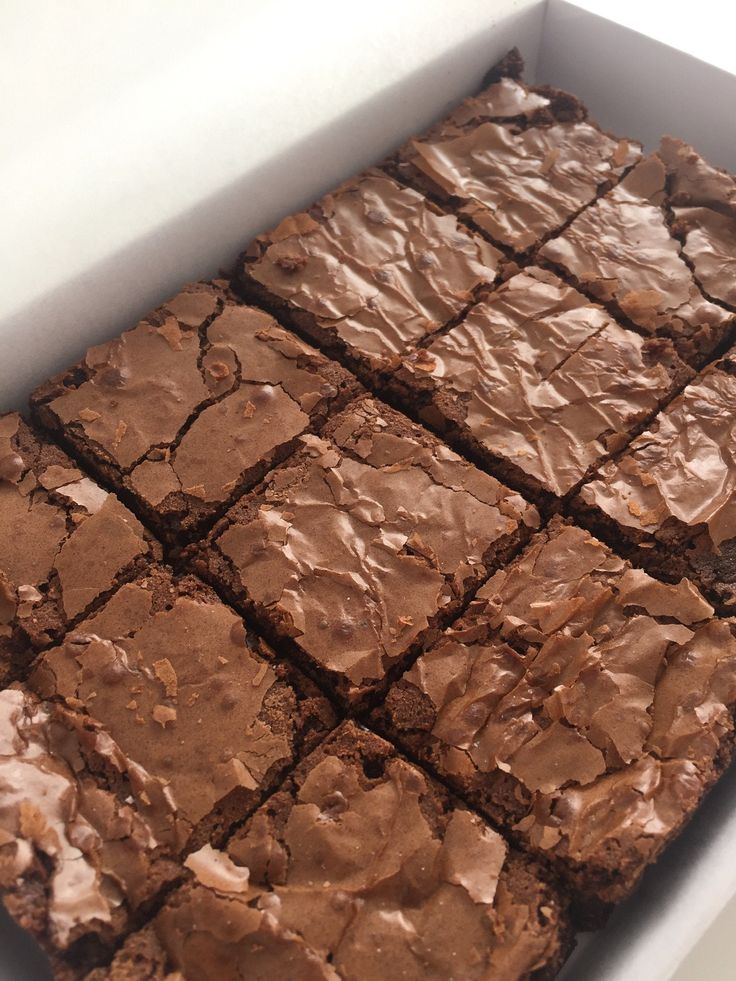 a box filled with brownies covered in chocolate frosting on top of a table