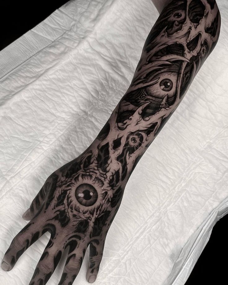 a person with tattoos on their arm and hand is holding an eyeball in front of them