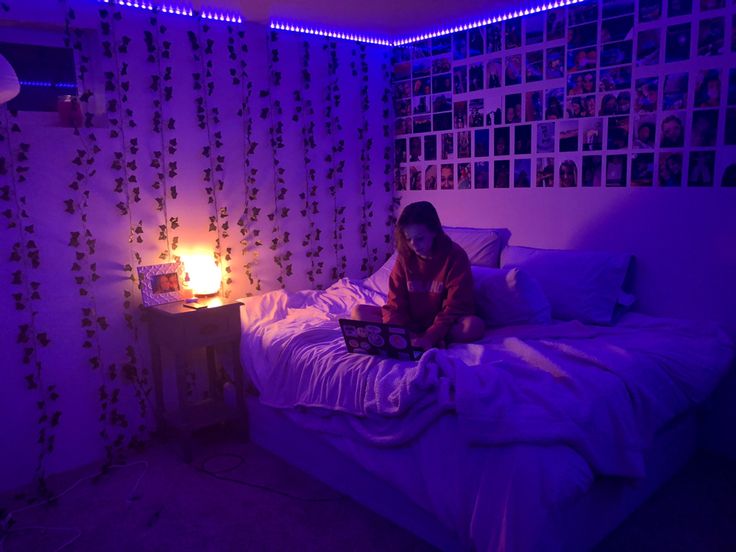 a woman is sitting on her bed with a laptop in front of the light that illuminates her