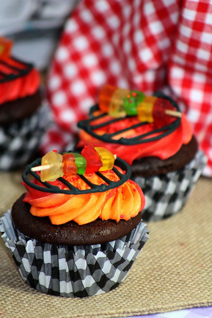 cupcakes decorated with candy and gummy bears on top of checkered paper