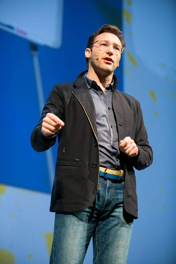 a man standing on stage with his hands in his pockets and looking at the camera