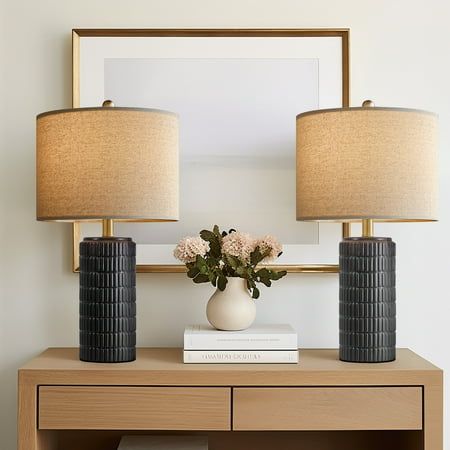 two vases with flowers on top of a table next to a mirror and lamp