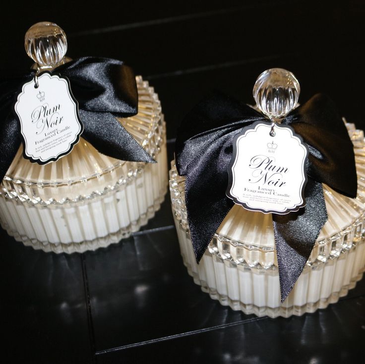 two small white cakes with black ribbons on them