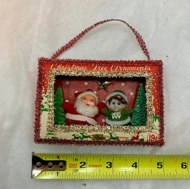 a christmas ornament hanging on a wall next to a ruler