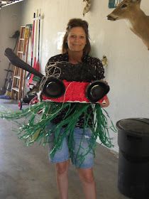 a woman standing in a garage holding a sign with deer heads on the wall behind her