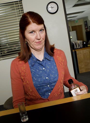 a woman sitting at a desk holding a bottle