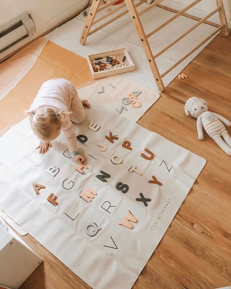 a toddler is playing with letters and numbers on the floor in front of a ladder