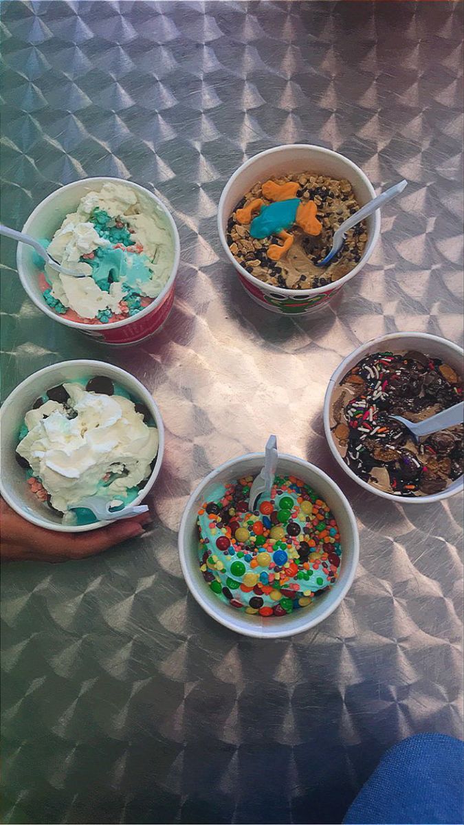 four bowls of ice cream with sprinkles and toppings in them on a table